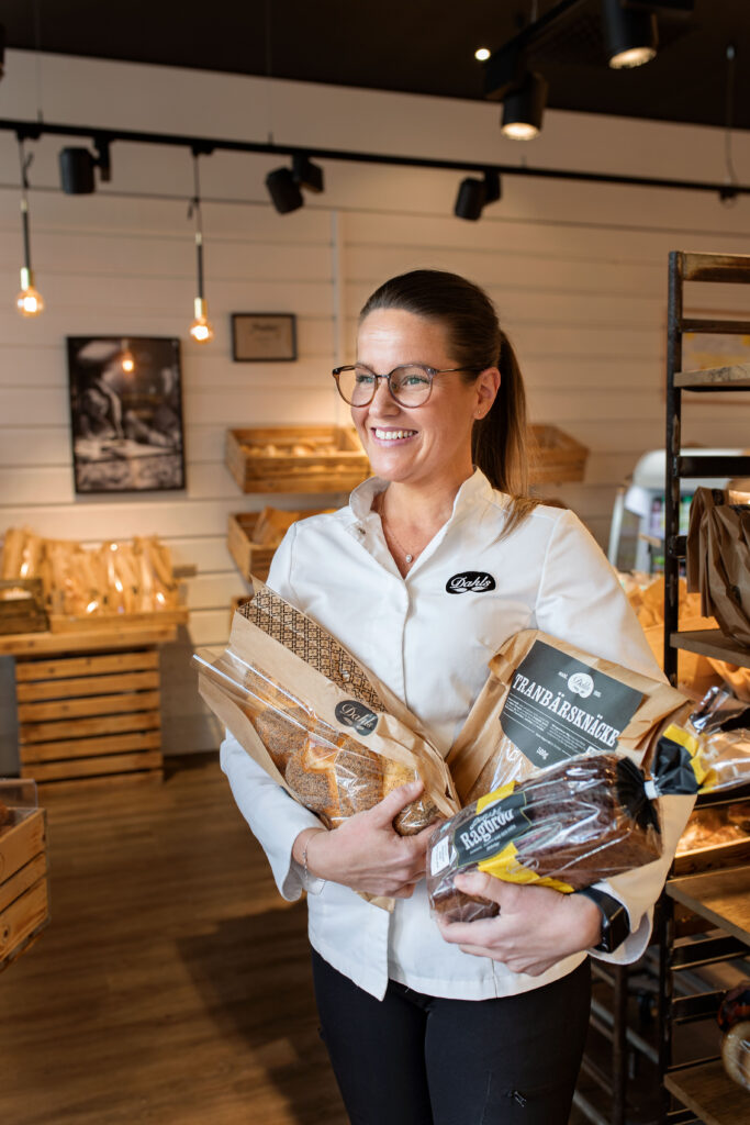 butikspersonal med bröd i famen i butiksmiljö
